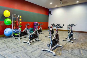 A gym with exercise equipment and a patterned carpet at The Retreat Apartment Homes in Williston, ND